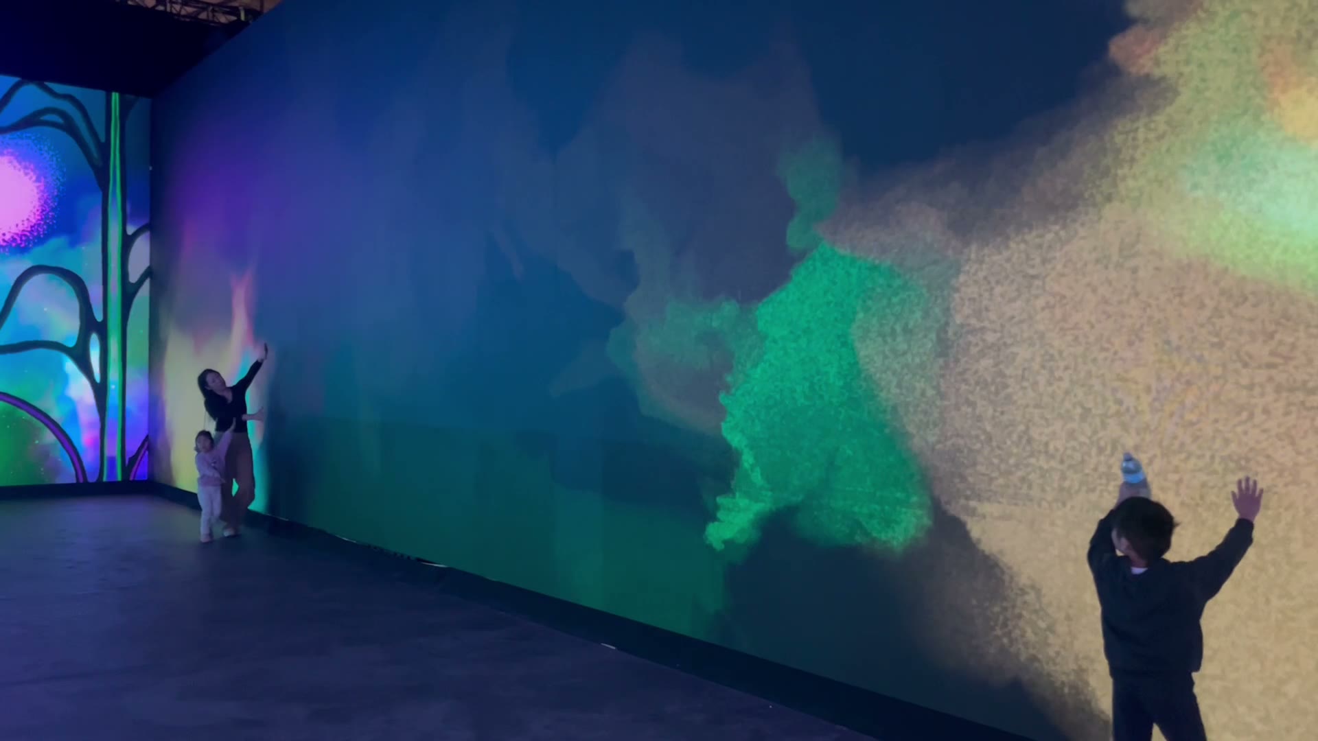 Guests move their arms through colourful particles projected across the Mythos wall