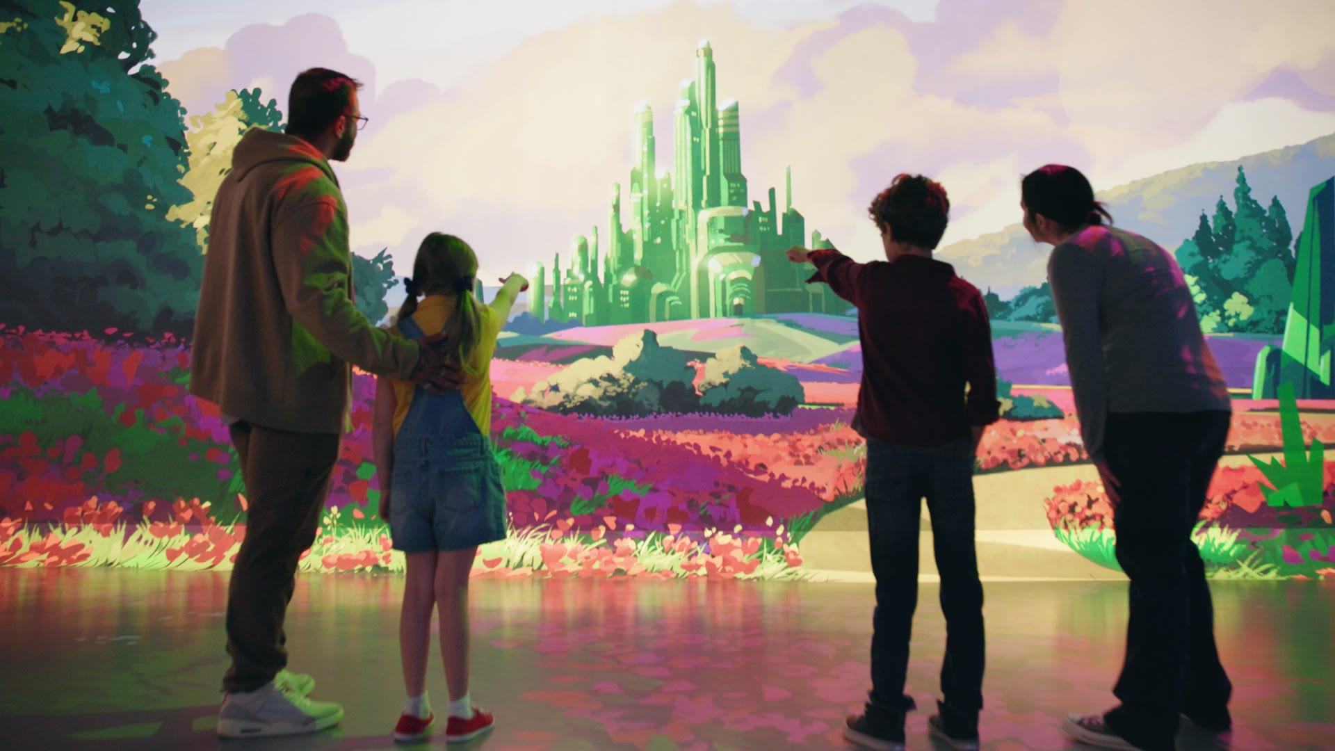 A family points toward the projected Emerald City in Journey to Oz