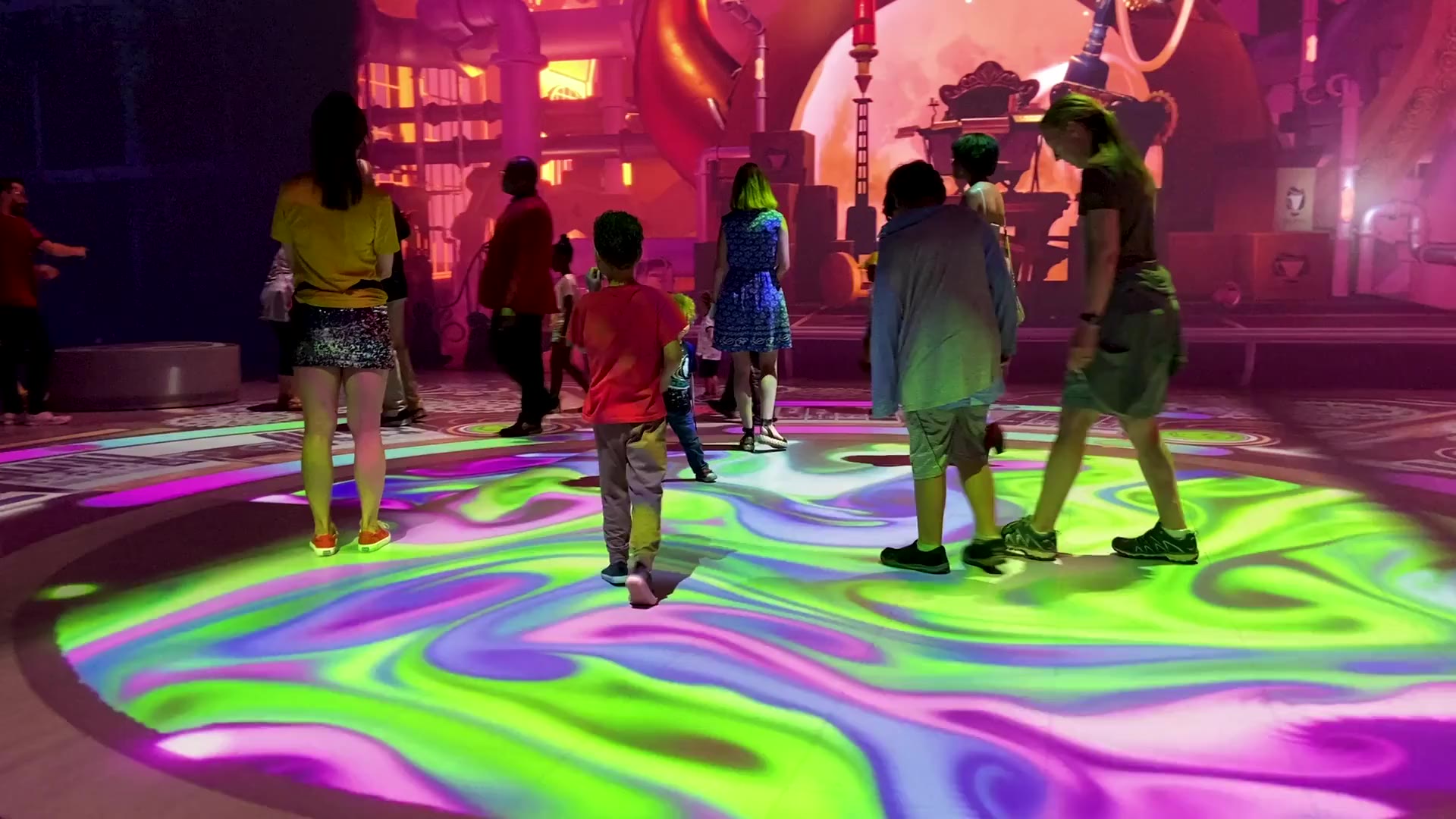 Children and families play on a swirling light floor in Waking Wonderland